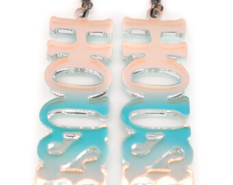 May include: A pair of silver earrings with a gradient design. The earrings are shaped like the word "HOME" in a stylised font. The gradient goes from white to light blue.