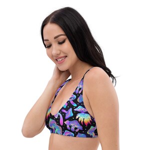 May include: Black bikini top with a colorful mushroom pattern. The mushrooms are in shades of blue, purple, and green, with a black background. The top has thin straps and a scoop neckline.