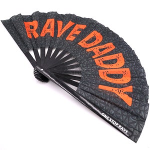 K&ouml;nnte beinhalten: Schwarzer Faltf&auml;cher mit den Worten "RAVE DADDY" in orangefarbenen Blockbuchstaben. Der F&auml;cher hat ein geometrisches Muster und den Text "ONE STOP RAVE" in Wei&szlig;.
