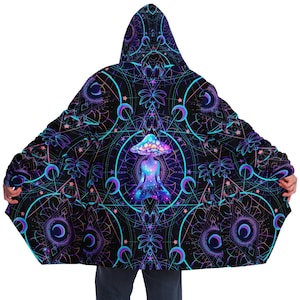Puede incluir: Una sudadera con capucha negra con un diseño psicodélico que presenta una figura brillante meditando dentro de un hongo. El diseño incluye formas geométricas, estrellas y lunas crecientes.