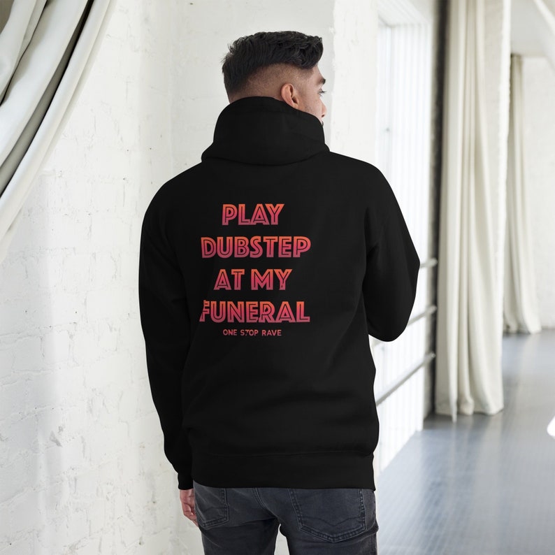 Pu&ograve; includere: Felpa con cappuccio nera con il testo "PLAY DUBSTEP AT MY FUNERAL" in un gradiente di rosso e arancione. Il testo "ONE STOP RAVE" &egrave; stampato in un carattere pi&ugrave; piccolo sotto il testo principale.