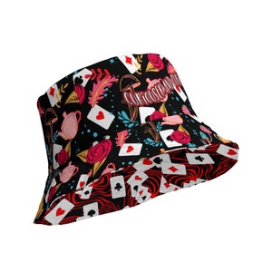 May include: Black bucket hat with a red, white, and black pattern of playing cards, roses, teacups, and mushrooms. The text "Curiouser and Curiouser" is printed on the hat.