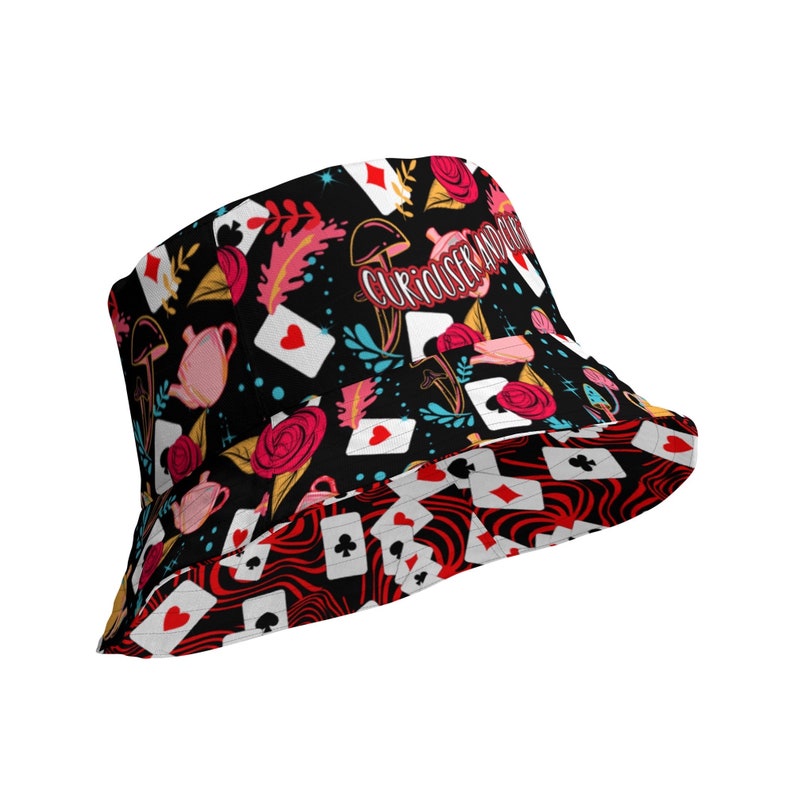 May include: Black bucket hat with a red, white, and black pattern of playing cards, roses, teacups, and mushrooms. The text "Curiouser and Curiouser" is printed on the hat.
