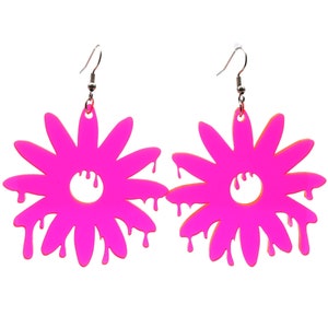 May include: A pair of pink acrylic earrings shaped like dripping flowers. The earrings have a silver hook.