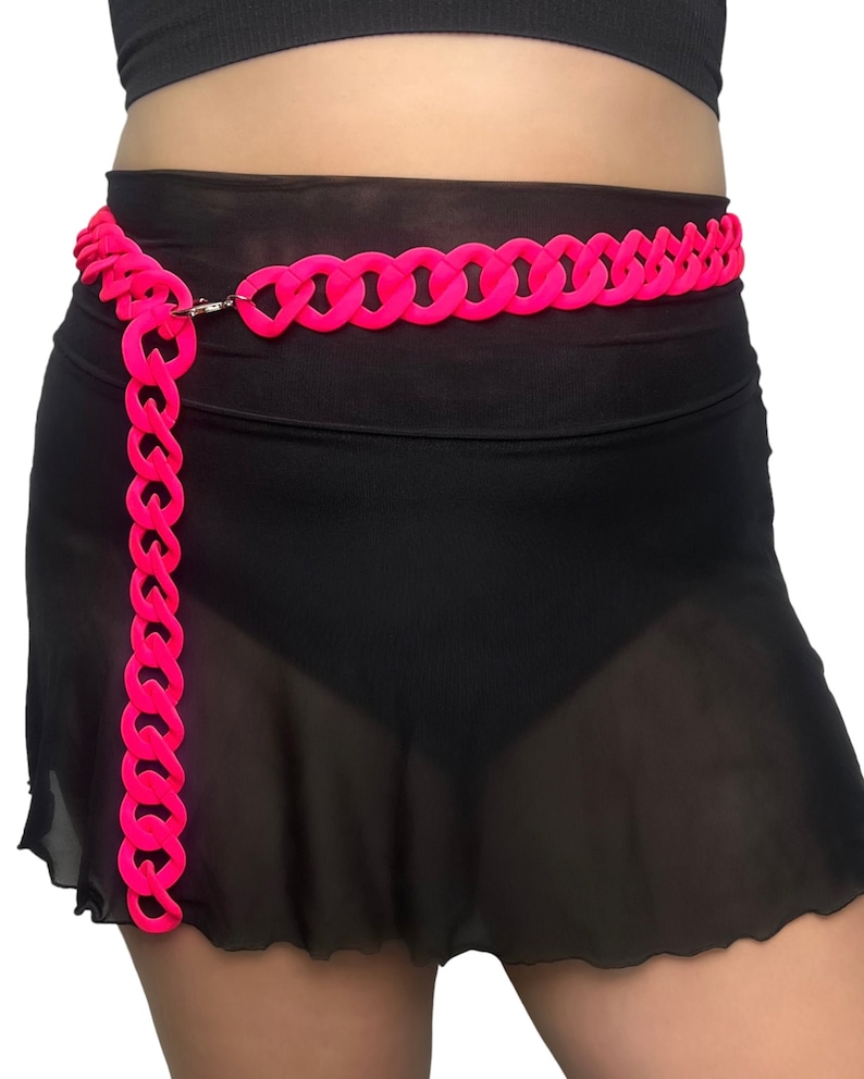 The model showcases a Colored Chunky Chain Belt in neon pink, adding a stylish touch to her festival outfit.