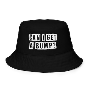 Könnte beinhalten: Schwarzer Bucket Hat mit dem Text "CAN I GET A BUMP?" in weißen Buchstaben.