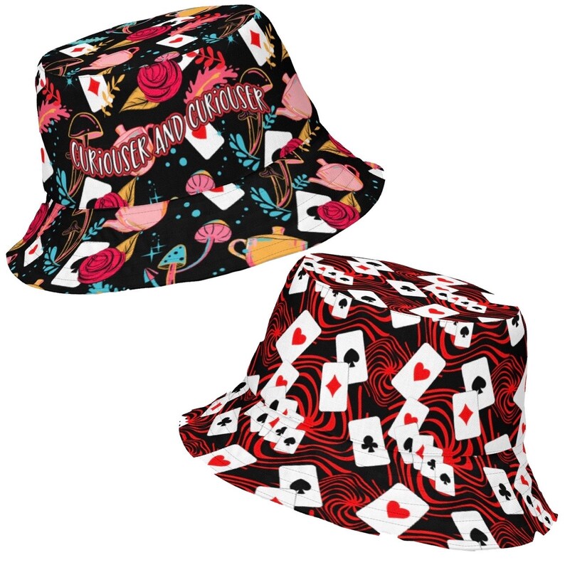 May include: Two black bucket hats with different designs. One hat features a black background with red roses, playing cards, mushrooms, and teacups. The text "Curiouser and Curiouser" is printed on the hat. The other hat features a black background with red and white playing cards on a swirling red pattern.