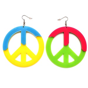 May include: A pair of peace sign earrings. The earrings are made of acrylic and are in the colours yellow, blue, green, and pink.
