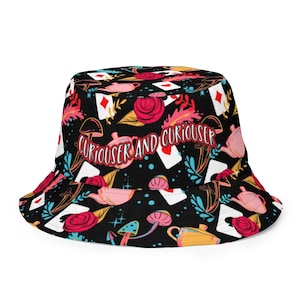 May include: Black bucket hat with a colorful pattern of teacups, playing cards, mushrooms, and roses. The text "Curiouser and Curiouser" is printed on the hat.