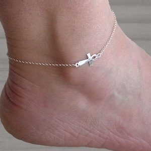 May include: A silver anklet with a small ankh charm. The anklet is made of a delicate chain and is perfect for layering with other jewellery.