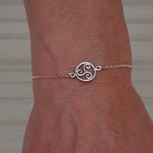 May include: A silver chain bracelet with a circular pendant featuring a Celtic knot design.