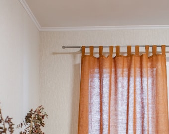Könnte beinhalten: Ein Paar rostfarbene Leinenvorhänge mit einer einfachen Stange und einem Tab-Oberteil, die an einem Fenster hängen. Die Vorhänge sind oben gerafft und hängen gerade herunter.