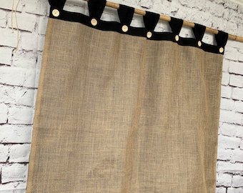May include: A brown burlap curtain with black trim and black buttons. The curtain has a ruffled bottom edge.