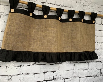 May include: A burlap valance with a black ruffle and black trim. The valance has five wooden buttons.