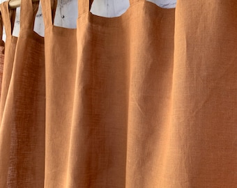 Könnte beinhalten: Ein Satz brauner Leinenvorhänge mit einem schlichten Design und rustikalem Flair. Die Vorhänge sind an einer Holzstange aufgehängt und haben einen gerafften Look.