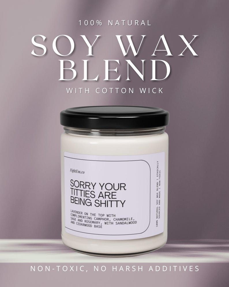 May include: A white soy wax candle in a clear glass jar with a black lid. The label reads: 100% NATURAL SOY WAX BLEND WITH COTTON WICK, SORRY YOUR TITTIES ARE BEING SHITTY, LAVENDER ON THE TOP WITH COMPLIMENTING CAMPHOR, CHAMOMILE, SAGE AND ROSEMARY.