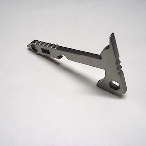 Könnte beinhalten: Ein silberfarbener Schlüsselanhänger in Form einer Axt mit einem Flaschenöffner und einer gezahnten Kante.