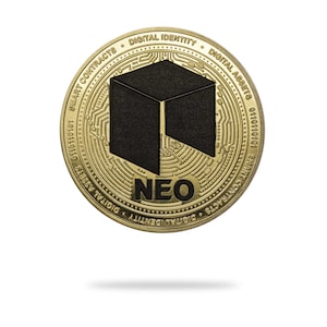 Puede incluir: Una moneda de color dorado con un logotipo en blanco y negro en el centro. La moneda tiene las palabras "DIGITAL IDENTITY", "SMART CONTRACTS", "DIGITAL ASSETS" y "NEO" inscritas alrededor del borde.