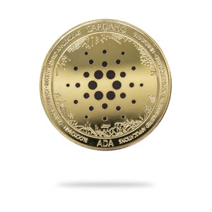 Puede incluir: Una moneda de criptomoneda Cardano de color dorado con la palabra "CARDANO" y el texto "BLOCKCHAIN - CRYPTOCURRENCY - DECENTRALIZED APPLICATIONS - IMPOSSIBLE" alrededor del borde. El centro de la moneda presenta un diseño en blanco y negro de un círculo con círculos más pequeños en su interior.