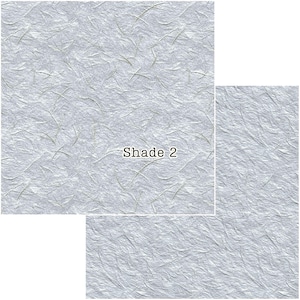 Puede incluir: Papel texturizado gris claro con sutiles fibras verdes y blancas. El papel tiene un aspecto arrugado y el texto "Shade 2" est&aacute; impreso en marr&oacute;n. El papel se muestra en tres tama&ntilde;os diferentes.