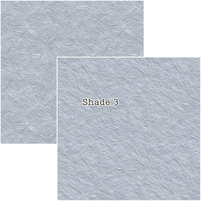 Puede incluir: Dos piezas rectangulares de papel azul claro texturizado con sutiles fibras doradas. La pieza m&aacute;s grande tiene el texto "Shade 3" en blanco, con una fuente sans-serif. El papel tiene un aspecto ligeramente arrugado, lo que sugiere un material hecho a mano o natural.