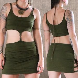 May include: Olive green two-piece outfit featuring a crop top and a mini skirt. The top has a scoop neckline and the skirt has cut-out details. The outfit is made of a soft, stretchy fabric. The model is wearing a necklace.