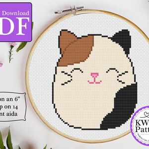 May include: Cross stitch pattern of a cute cartoon cat with brown, white, and black fur. The pattern is designed to fit on a 6-inch hoop and uses 14 count Aida cloth.