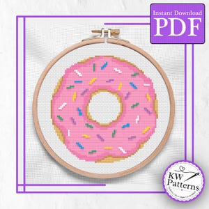 May include: A cross-stitch pattern of a pink donut with colorful sprinkles, set in a wooden embroidery hoop. The design is on white fabric, with a purple border and the text "Instant Download PDF".
