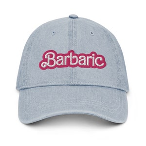 May include: A light blue denim baseball cap with the word "Barbaric" embroidered in pink with white outlines.