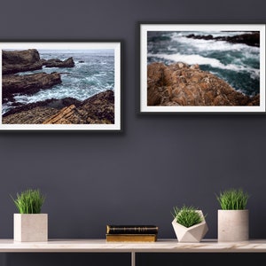 May include: Two framed photographs of a rocky coastline with crashing waves. The top photo shows a close-up of the rocks and waves, while the bottom photo shows a wider view of the coastline.