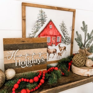 May include: A wooden sign with the text "Happy Holidays" in white lettering, a red cabin with snow on the roof, and a Christmas tree with red berries and a gold ornament.