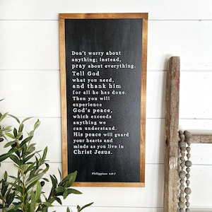 May include: A black framed chalkboard sign with white text that reads "Don't worry about anything; instead, pray about everything. Tell God what you need, and thank him for all he has done. Then you will experience God's peace, which exceeds anything we can understand. His peace will guard your hearts and minds as you live in Christ Jesus." The bottom of the sign reads "Philippians 4:6-7".