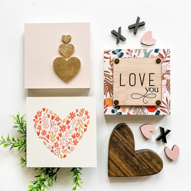 May include: A set of five wooden signs with a Valentine's Day theme. The signs feature hearts, floral patterns, and the words "Love You".