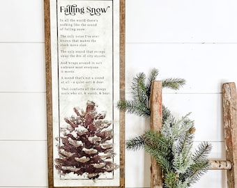 May include: A framed print with a vintage aesthetic featuring a pine cone covered in snow. The print includes a poem about the sound of falling snow.
