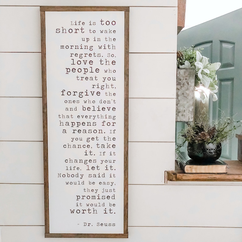 May include: A wooden sign with a white background and black text. The sign features a quote by Dr. Seuss that reads: "Life is too short to wake up in the morning with regrets. So, love the people who treat you right, forgive the ones who don't and believe that everything happens for a reason. If you get the chance, take it. If it changes your life, let it. Nobody said it would be easy. They just promised it would be worth it. - Dr. Seuss"
