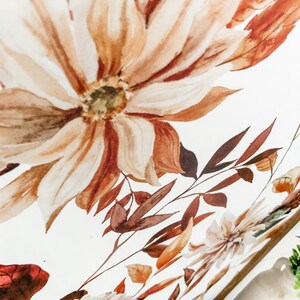Peut inclure: Peinture &agrave; l'aquarelle d'une grande fleur brun clair &agrave; multiples p&eacute;tales. La fleur est entour&eacute;e de feuilles et de tiges brunes et brun rouge&acirc;tre. L'&oelig;uvre d'art a une palette de couleurs douces et chaudes, avec un fond blanc.