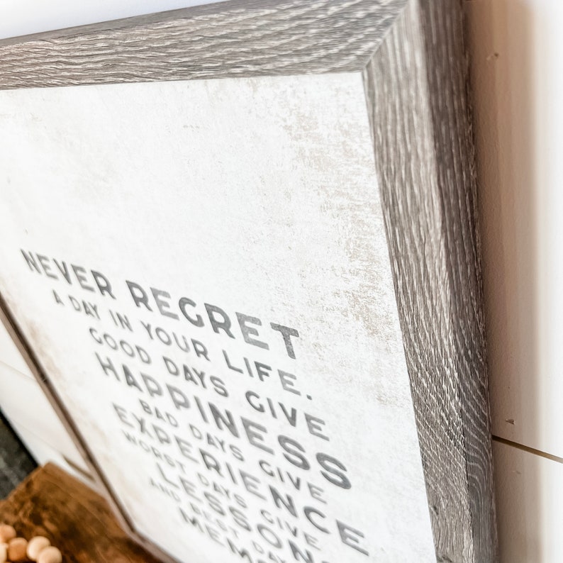 May include: A framed wood sign with a white background and black text that reads "Never Regret a Day in Your Life. Good Days Give Happiness. Bad Days Give Experience. Worst Days Give Lessons. And Best Days Give Memories."