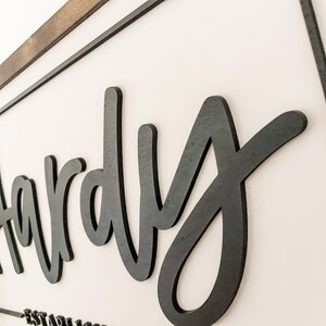 May include: Black wooden sign with the word "Hardy" in a cursive font.
