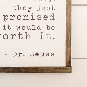 May include: A framed print with a white background and a black and white quote from Dr. Seuss that reads "It's not easy, they just promised it would be worth it."