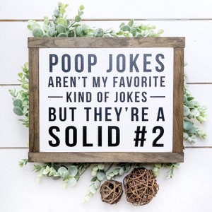 Puede incluir: Un letrero de madera con fondo blanco y texto negro que dice "Poop Jokes Aren't My Favorite Kind of Jokes - But They're A Solid #2".