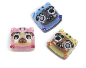 May include: Three ceramic pug figurines with different colored bodies. The pugs are all wearing a hooded sweater. The pugs are blue, pink, and yellow.