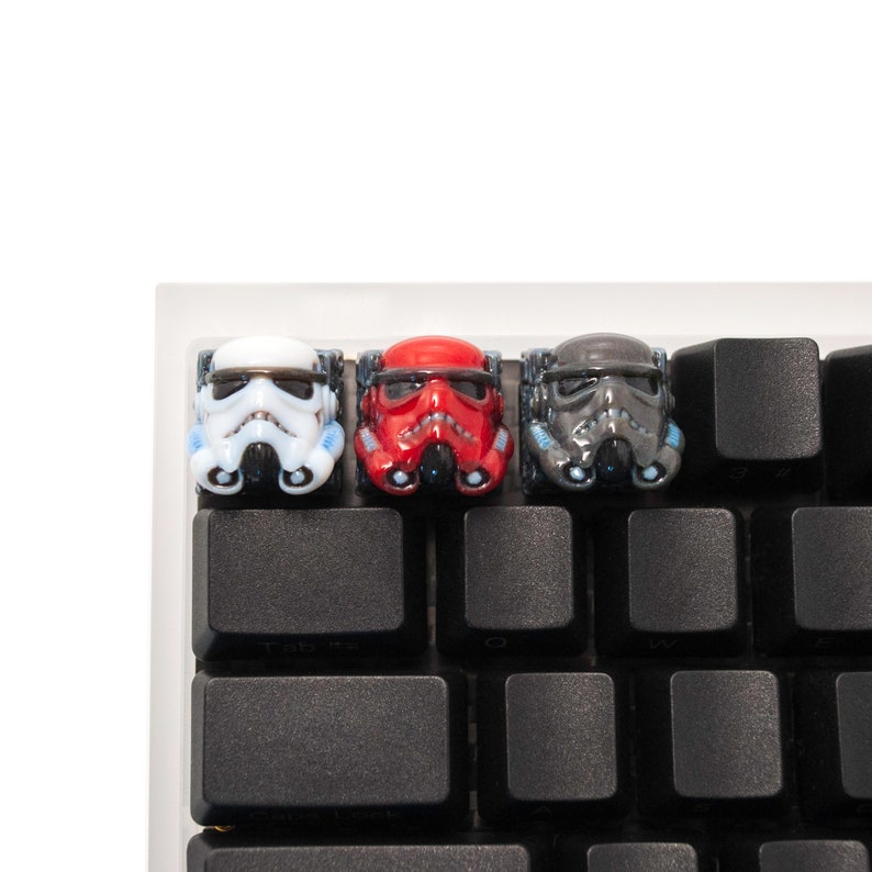 Op de afbeelding: Drie Star Wars-personage toetsencaps in wit, rood en zwart. De toetsencaps bevinden zich op een zwart toetsenbord.