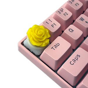 Pu&ograve; includere: Un copritasto a forma di rosa gialla per una tastiera meccanica rosa. Il copritasto &egrave; una sostituzione per il tasto standard "Tab".