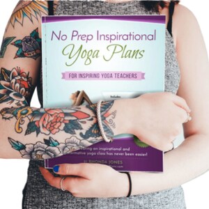 May include: A woman with tattoos holds a purple and blue book titled "No Prep Inspirational Yoga Plans for Inspiring Yoga Teachers". The book includes a photo of a woman in a yoga pose.