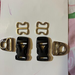 Puede incluir: Surtido de cierres y hebillas de metal dorado y negro. Los cierres tienen forma de ocho. Las hebillas son rectangulares con un anillo en D en un extremo.