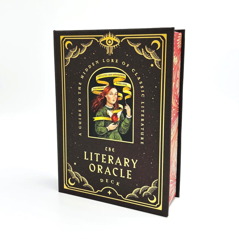 May include: A dark brown book with gold accents and the title "The Literary Oracle Deck." The cover features an illustration of a woman and the text "A Guide to the Hidden Lore of Classic Literature."