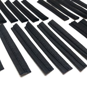 May include: A collection of black fabric trim with a stitched edge. The trim is arranged in rows on a white surface.