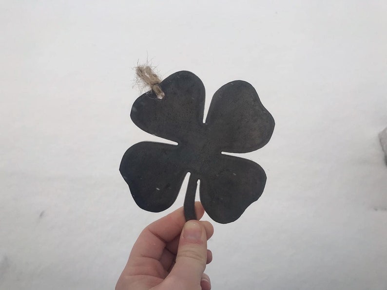 May include: A black metal four-leaf clover cutout with a twine loop for hanging.