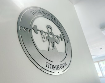 May include: A silver metal sign with a silhouette of a person lifting weights. The sign reads "YOUR NAME HERE EST 123 HOME GYM".