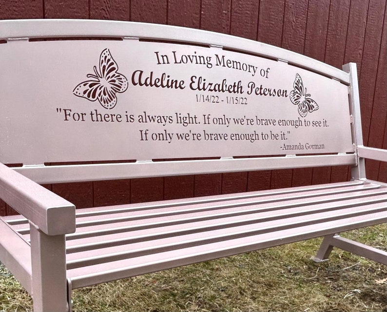 Puede incluir: Un banco de metal rosa con una inscripci&oacute;n conmemorativa. La inscripci&oacute;n dice: "In Loving Memory of Adeline Elizabeth Peterson 1/14/22-1/15/22" e incluye una cita de Amanda Gorman: "Porque siempre hay luz. Si solo somos lo suficientemente valientes para verla. Si solo somos lo suficientemente valientes para serla."